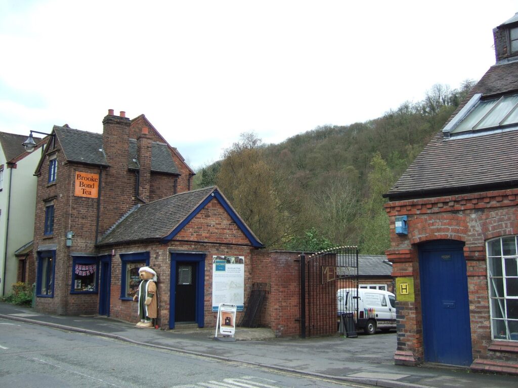 Brick buildings of the Merrythought site in Ironbridge, Shropshire, with a large teddy bear figure by the shop door