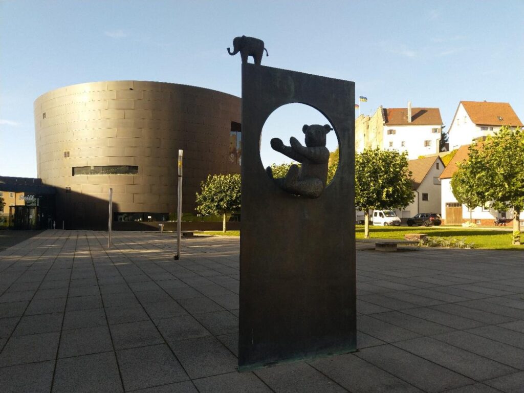 Round bronze-clad Steiff Museum building in Giengen with a teddy bear sculpture in the foreground